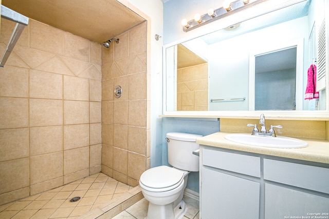 bathroom featuring tile patterned flooring, vanity, tiled shower, and toilet