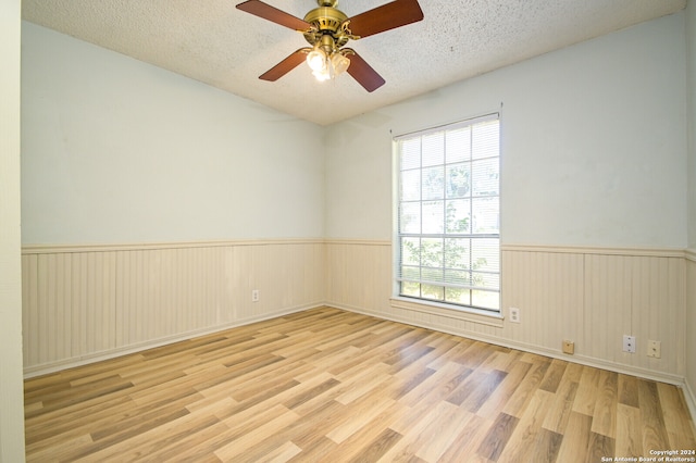 spare room featuring ceiling fan, light wood-type flooring, and a textured ceiling