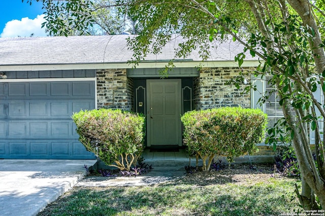 doorway to property with an attached garage, stone siding, a shingled roof, and board and batten siding