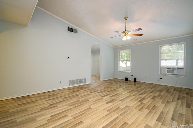 spare room featuring lofted ceiling, arched walkways, wood finished floors, and visible vents