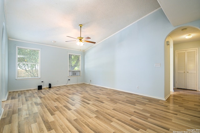 empty room featuring ceiling fan, light hardwood / wood-style flooring, a textured ceiling, crown molding, and lofted ceiling