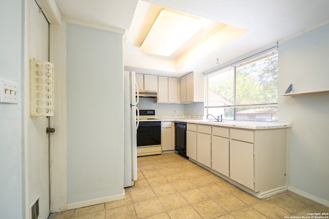 kitchen featuring a tray ceiling, cream cabinets, light tile patterned floors, sink, and white appliances