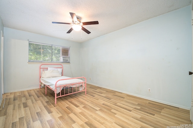 bedroom featuring ceiling fan, light wood-type flooring, and a textured ceiling