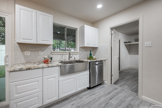 kitchen featuring backsplash, dishwasher, light hardwood / wood-style floors, light stone countertops, and white cabinets