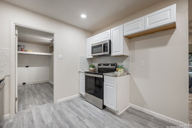 kitchen featuring appliances with stainless steel finishes, light stone counters, light hardwood / wood-style floors, tasteful backsplash, and white cabinets