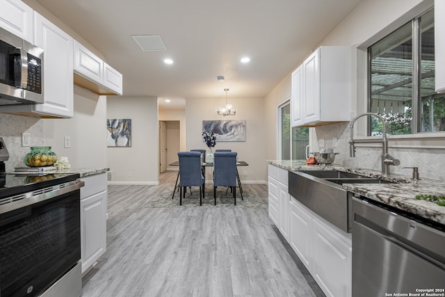 kitchen with appliances with stainless steel finishes, light hardwood / wood-style flooring, decorative backsplash, light stone counters, and white cabinets