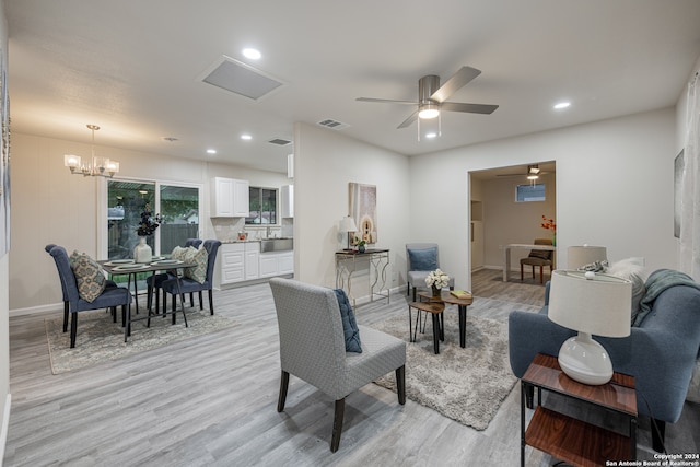 living room with light hardwood / wood-style floors and ceiling fan with notable chandelier