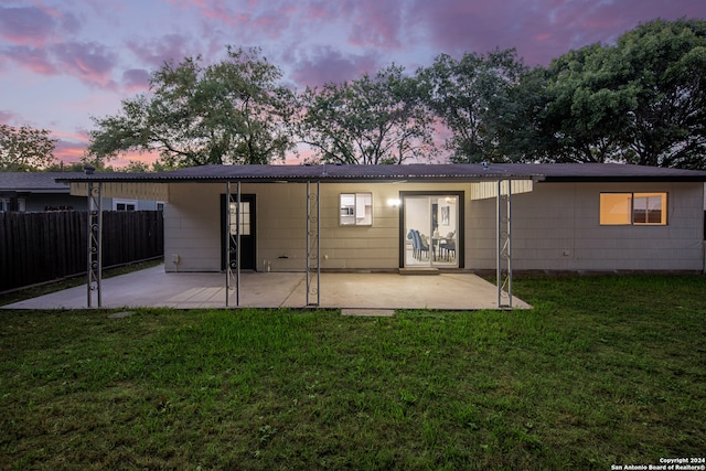 back house at dusk with a lawn