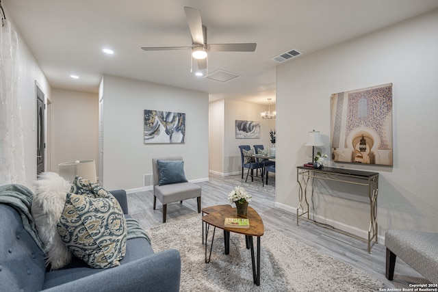 living room with light hardwood / wood-style floors and ceiling fan with notable chandelier