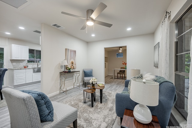 living room featuring ceiling fan, sink, and light hardwood / wood-style floors