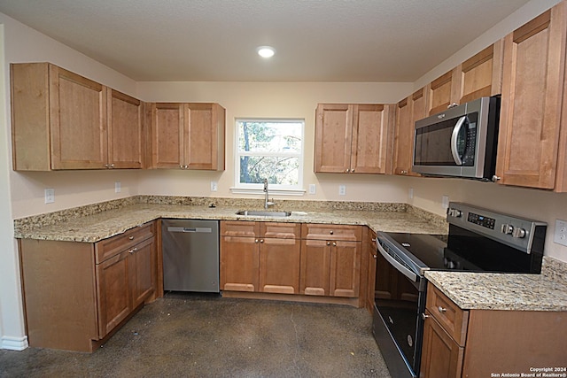 kitchen featuring light stone countertops, appliances with stainless steel finishes, and a sink