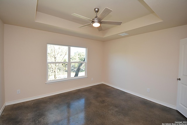 unfurnished room with a raised ceiling, visible vents, ceiling fan, concrete flooring, and baseboards