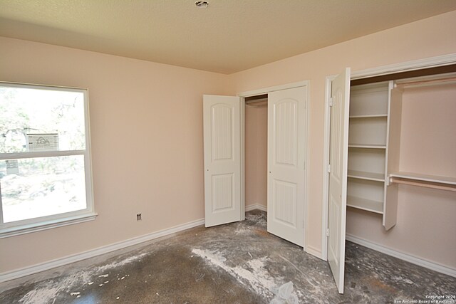 unfurnished bedroom featuring concrete floors and baseboards