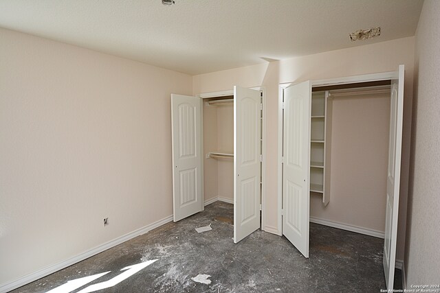 unfurnished bedroom featuring a textured ceiling, baseboards, and a closet