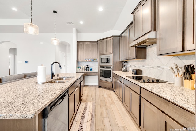 kitchen with light hardwood / wood-style flooring, backsplash, appliances with stainless steel finishes, light stone counters, and sink