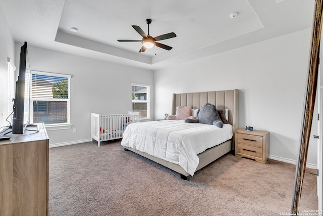 bedroom featuring a tray ceiling, carpet floors, and ceiling fan