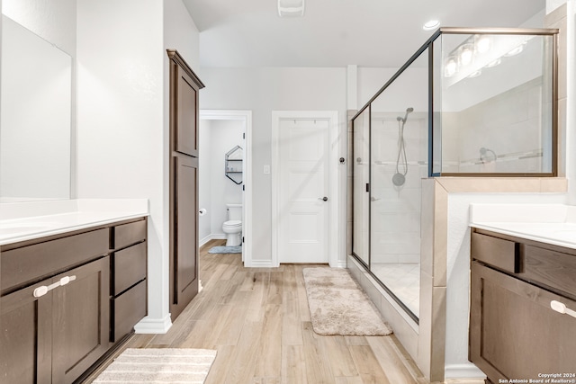 bathroom featuring a shower with shower door, toilet, hardwood / wood-style floors, and vanity