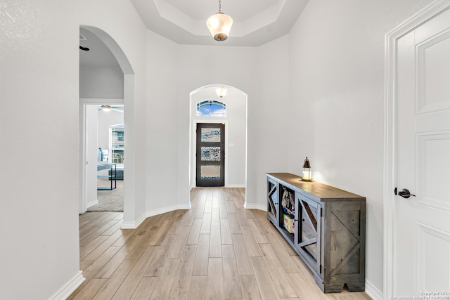 entrance foyer with light hardwood / wood-style floors and a tray ceiling