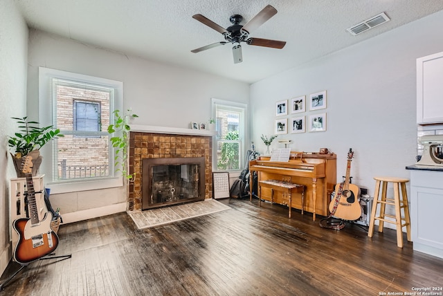 living room with ceiling fan, dark wood-type flooring, and a textured ceiling