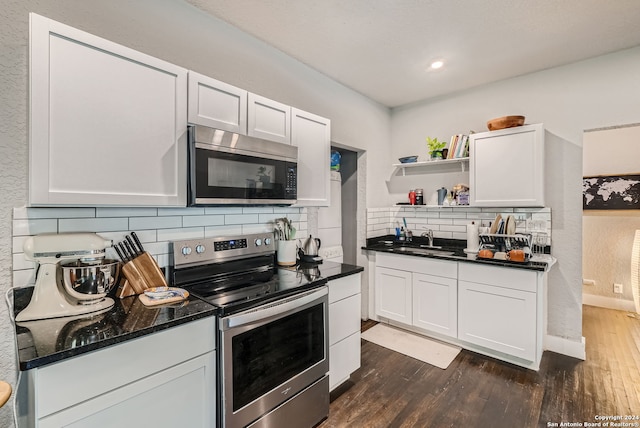 kitchen with dark hardwood / wood-style flooring, tasteful backsplash, white cabinetry, and stainless steel appliances