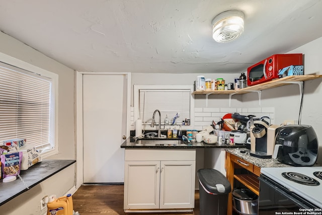 kitchen with sink, white cabinets, dark hardwood / wood-style flooring, and dark stone counters