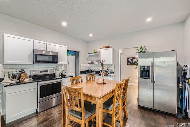 kitchen with backsplash, stainless steel appliances, white cabinetry, a textured ceiling, and dark wood-type flooring