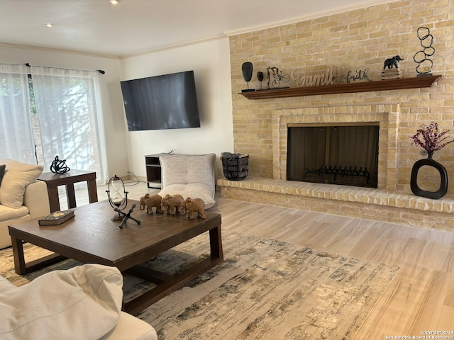 living room with light hardwood / wood-style floors, crown molding, brick wall, and a fireplace