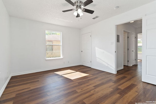 empty room with ceiling fan, dark wood-type flooring, and a textured ceiling