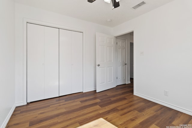 unfurnished bedroom featuring ceiling fan, a closet, a textured ceiling, and dark wood-type flooring