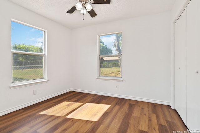 unfurnished bedroom with ceiling fan, dark hardwood / wood-style floors, a closet, and a textured ceiling