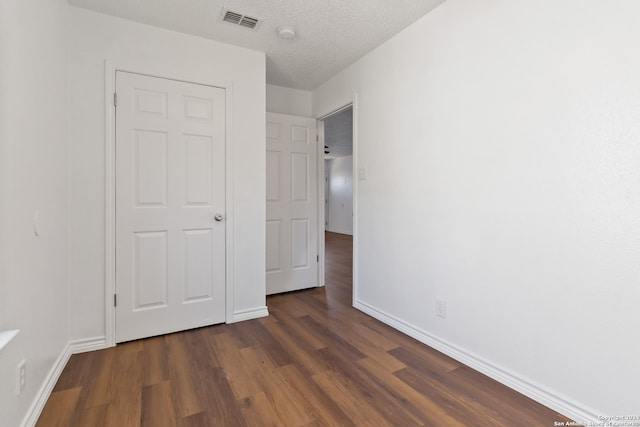 unfurnished bedroom featuring a textured ceiling and dark wood-type flooring