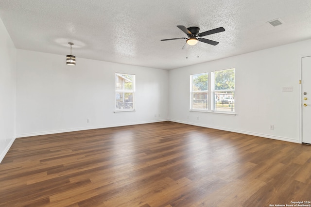 unfurnished room featuring a textured ceiling, a healthy amount of sunlight, and dark hardwood / wood-style flooring