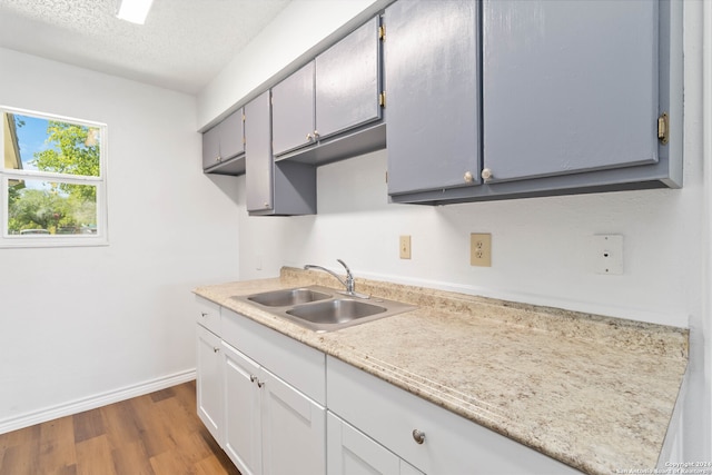 kitchen featuring sink, gray cabinetry, a textured ceiling, and dark hardwood / wood-style floors