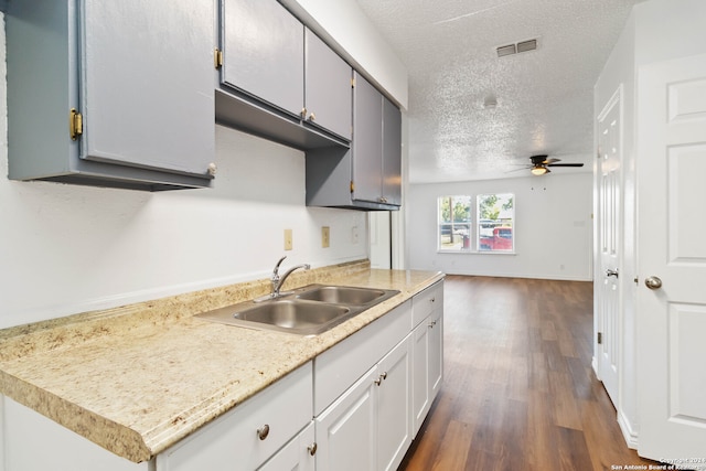 kitchen featuring sink, a textured ceiling, gray cabinetry, dark hardwood / wood-style flooring, and ceiling fan