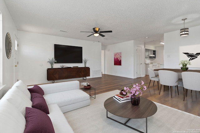 living room with ceiling fan, hardwood / wood-style flooring, and a textured ceiling