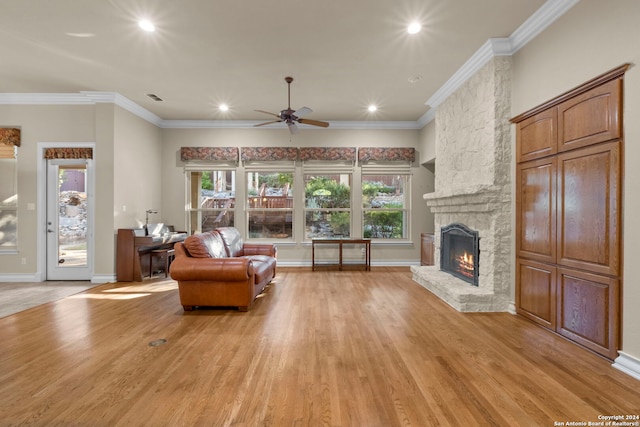 living room featuring a stone fireplace, light wood-type flooring, and crown molding