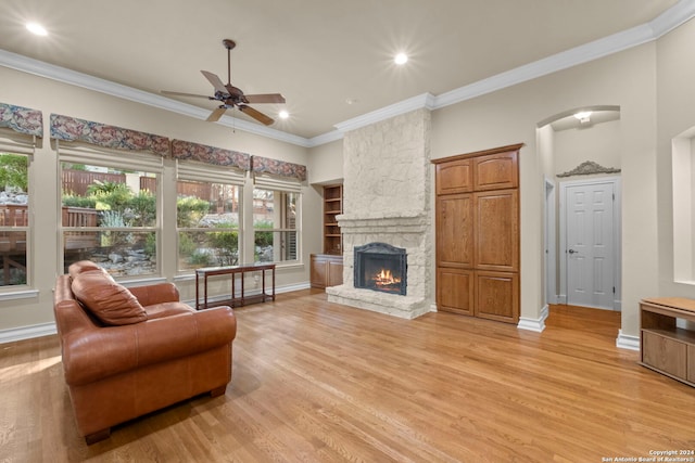 living room with ceiling fan, light hardwood / wood-style floors, a fireplace, and crown molding