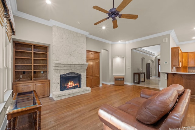 living room with ornamental molding, light hardwood / wood-style floors, a fireplace, and ceiling fan