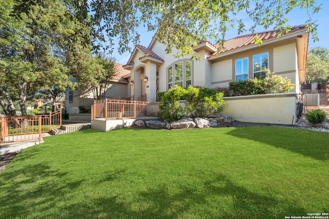 mediterranean / spanish-style house with a deck, a front lawn, and central AC unit