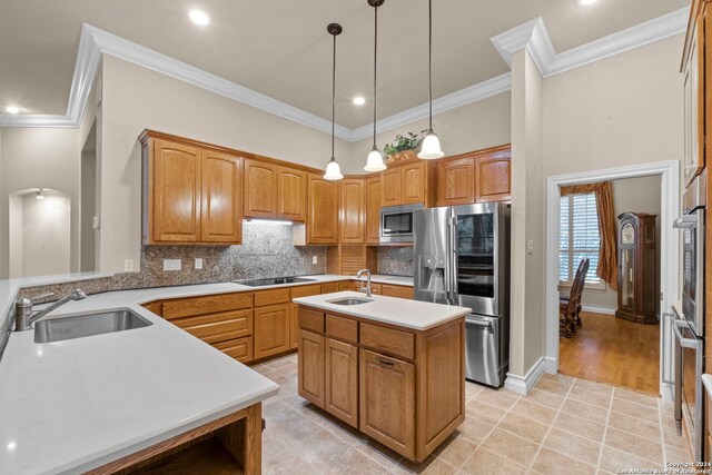 kitchen with a center island with sink, ornamental molding, sink, and stainless steel appliances