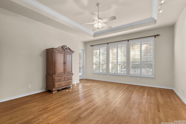 spare room with ceiling fan, ornamental molding, a raised ceiling, and light hardwood / wood-style floors