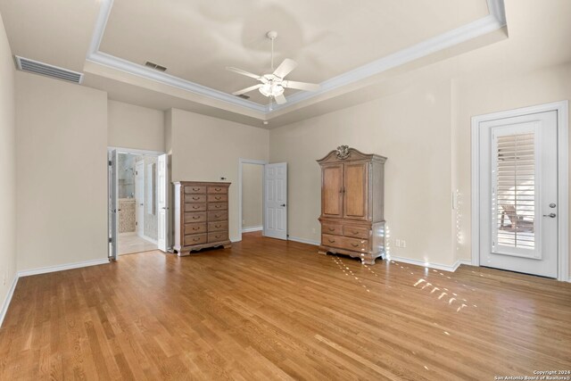 interior space with light hardwood / wood-style flooring, a tray ceiling, ceiling fan, and ensuite bath