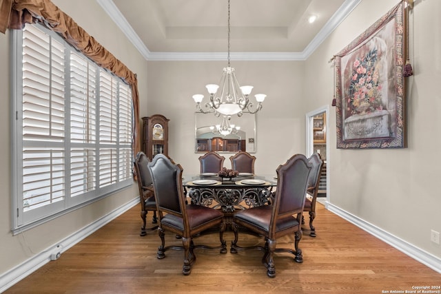 dining area with wood-type flooring, a tray ceiling, a chandelier, and a wealth of natural light