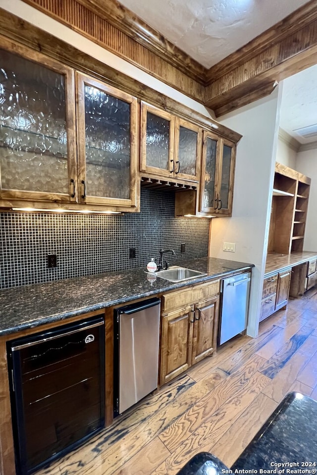 kitchen featuring sink, decorative backsplash, light hardwood / wood-style floors, stainless steel dishwasher, and beverage cooler