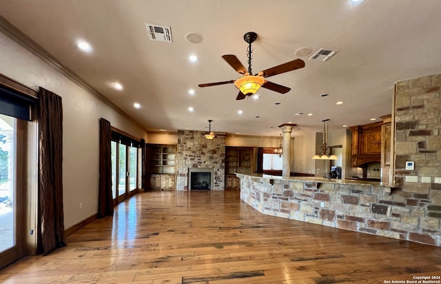 kitchen with a fireplace, light hardwood / wood-style floors, ceiling fan, crown molding, and kitchen peninsula