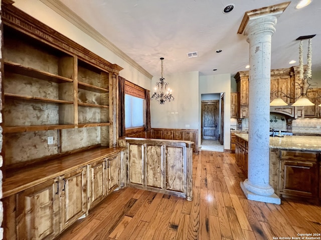 kitchen with light hardwood / wood-style floors, light stone countertops, ornate columns, a notable chandelier, and hanging light fixtures