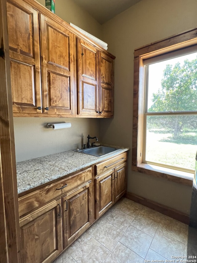 kitchen with sink, light stone countertops, and light tile patterned floors