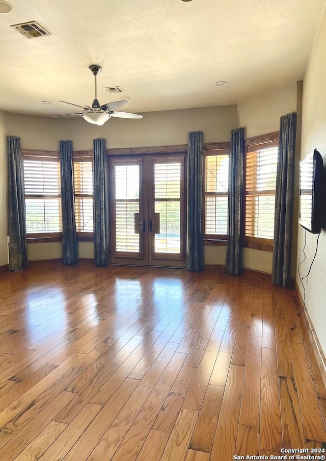 unfurnished living room featuring ceiling fan, french doors, and wood-type flooring