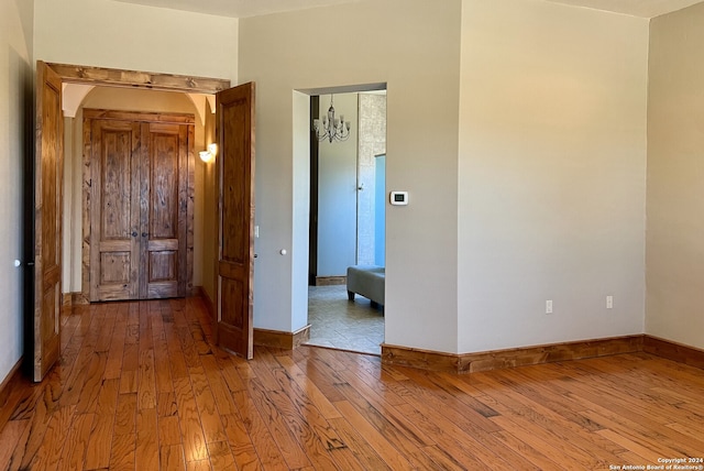 unfurnished room with a notable chandelier and hardwood / wood-style floors