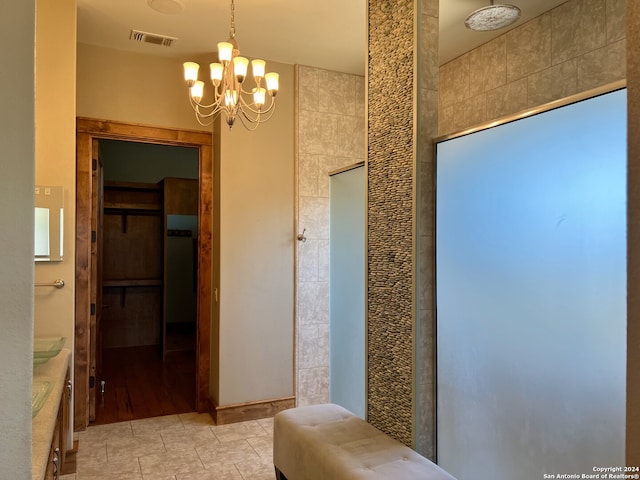 bathroom with vanity, hardwood / wood-style floors, tile walls, walk in shower, and an inviting chandelier